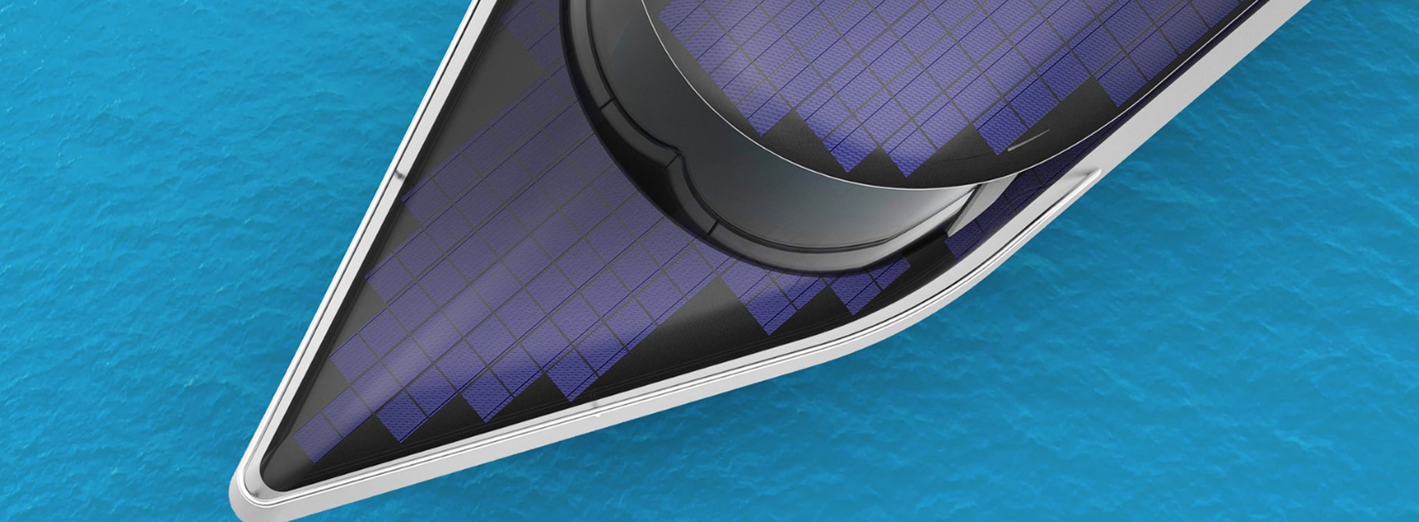 Dziób jachtu EnerBoat z panelami fotowoltaicznymi zintegrowanymi z poszyciem, widziany z góry na tle turkusowej wody